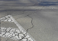 Asphalt shrinkage cracking sprawls randomly across the asphalt, a result of quick and hot curing "pulling" the asphalt apart and splitting it.