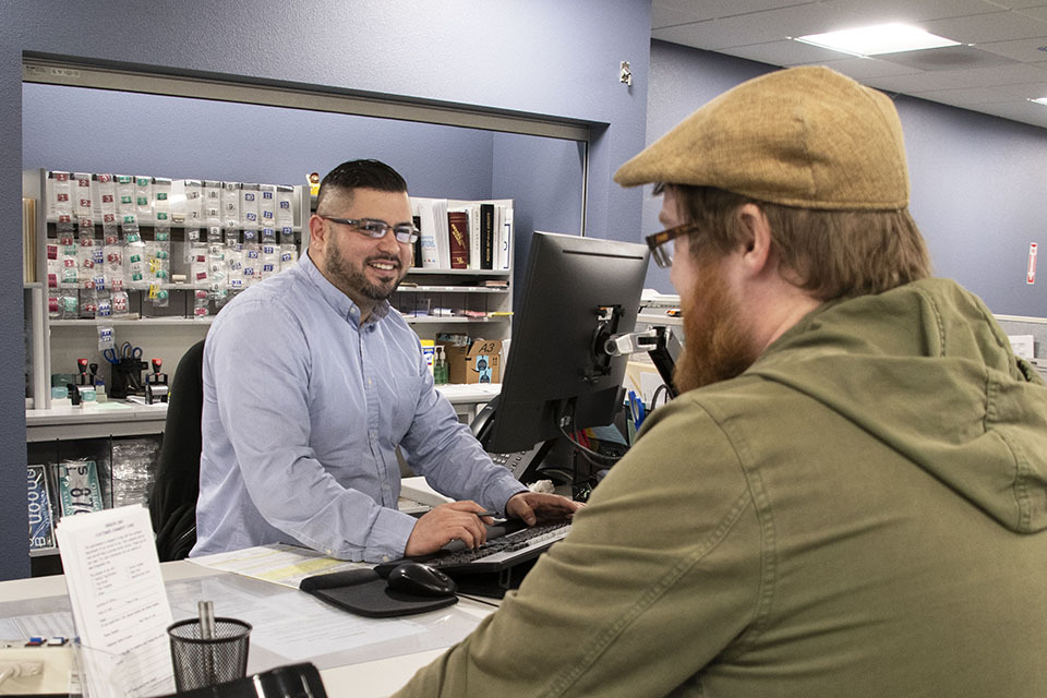 Image of DMV employee helping customer at service counter