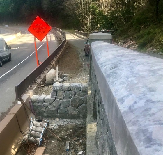 A stone wall fills the gap between the concrete barrier of I-84 and the new trail. 