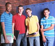 Four mail teens standing next to lockers at school