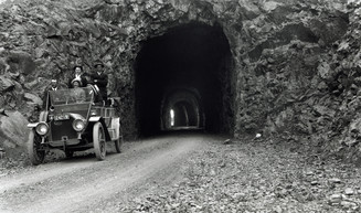 A historic photo of original Mitchell Point Tunnel with a vintage car leaving the portal. 