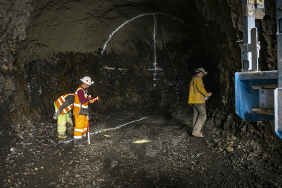 Three crew members are in a large 18-foot tunnel with spray paint on the back. 