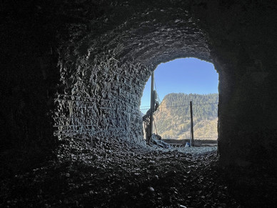 A large, arched window in rock letting in light to the tunnel. 
