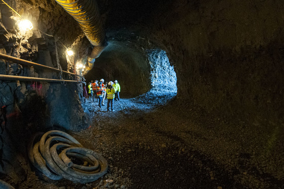 People stand in the Mitchell Point Tunnel with an arched window in rock letting light in.