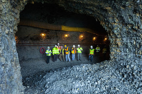People are framed standing in the Mitchell Point Tunnel by an arched window in rock