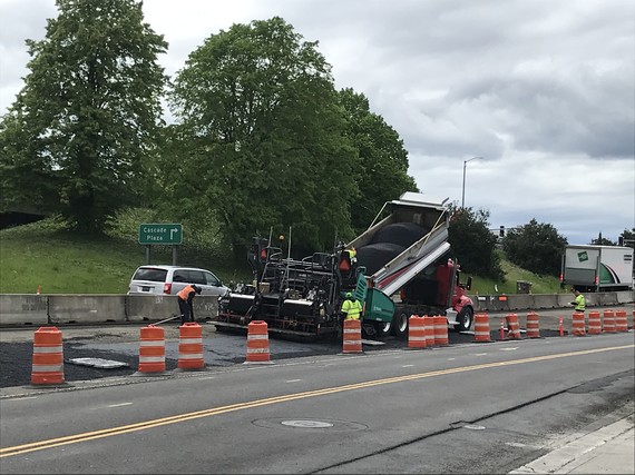 Crews lay fresh asphalt along the side of the highway