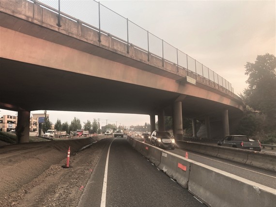 View from the shoulder of OR 217 with a concrete barrier between the work zone and travel lane and the Scholls Ferry Road overpass above.