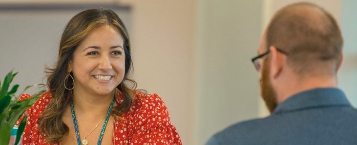 woman at a desk smiling while talking with a man