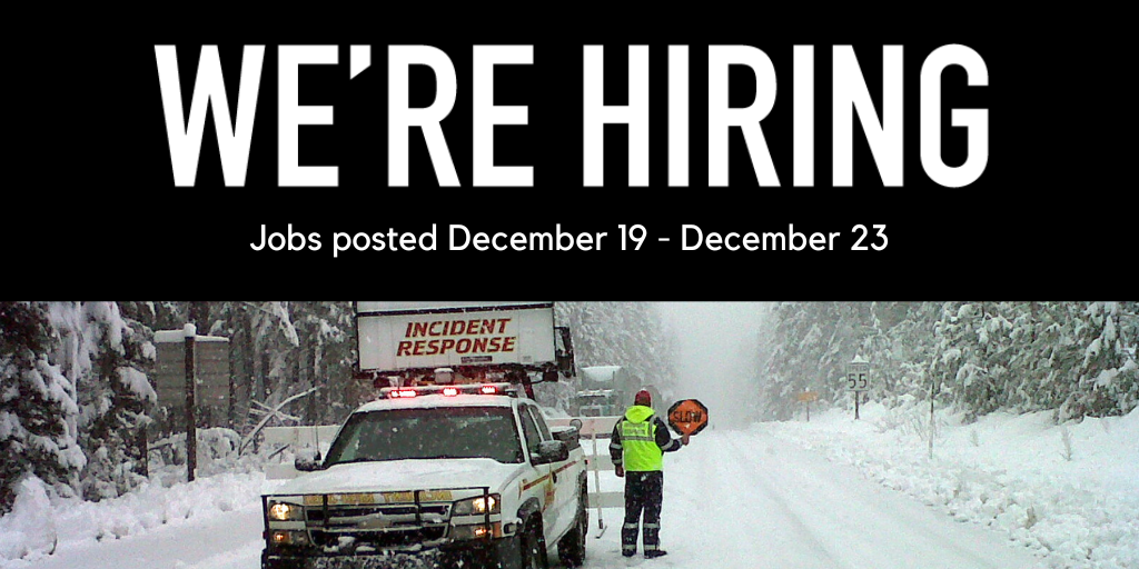 Snowy road and snowy trees with a large plow truck and an ODOT worker holding a sign that reads - SLOW