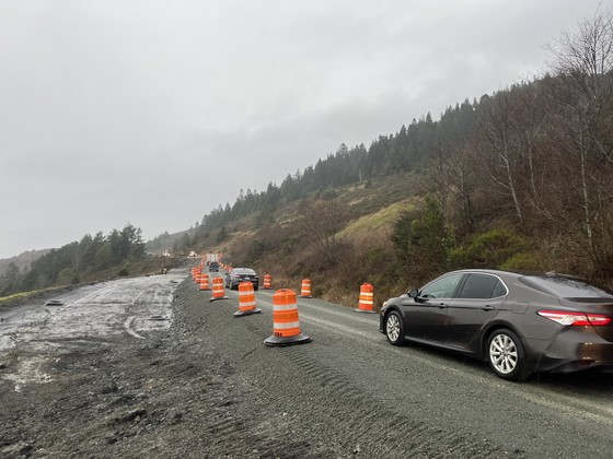Traffic drives on a gravel lane through U.S. 101 slide area