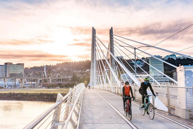 Two people bike across the Tilikum Bridge in Portland