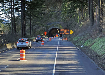 Workers in roadway sign in front of Toothrock Tunnel. The right lane is closed. 