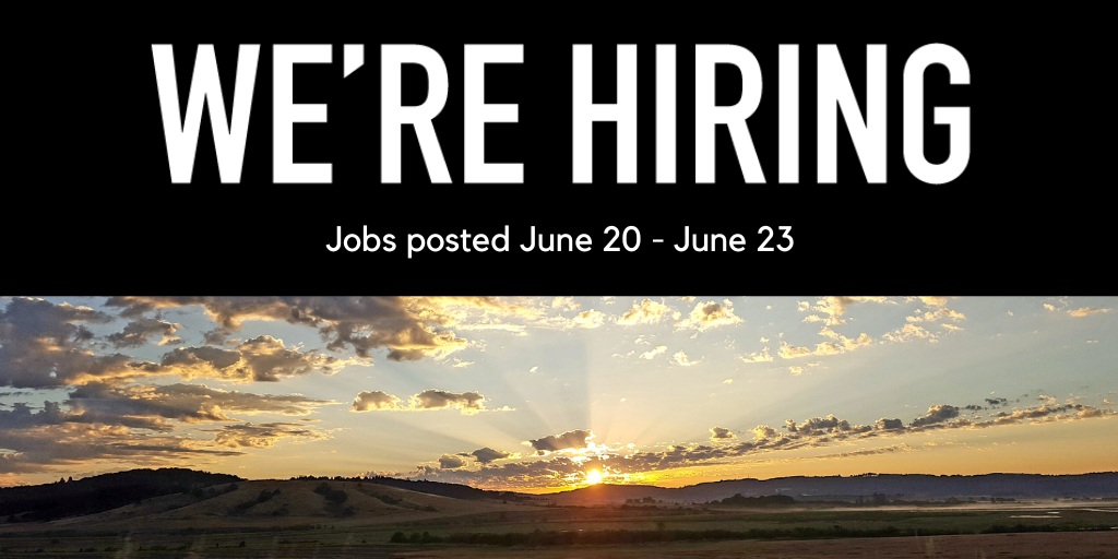 Photo of the sun setting behind rolling hills and grass fields, with scattered clouds. 