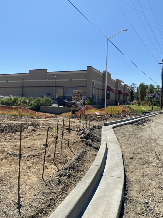 A length of concrete curb lining the excavated roadway in front of Tractor Supply.