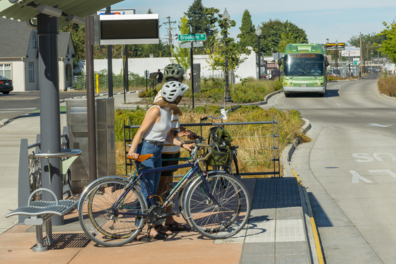 Two bicycle users wait at a bus station