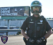 Officer standing in front of billboard that says Don't drive distracted
