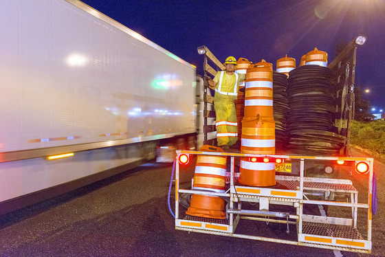 Crews setting up a work zone with orange cones in advance to highway maintenance only feet from moving traffic.