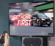 Image of vehicle traveling fast on a TV screen with the text "GET HOME FIRST"