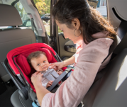 Parent installing a rear facing child car seat in vehicle