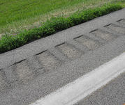 Grooved pavement rumble strips with green grass on shoulder