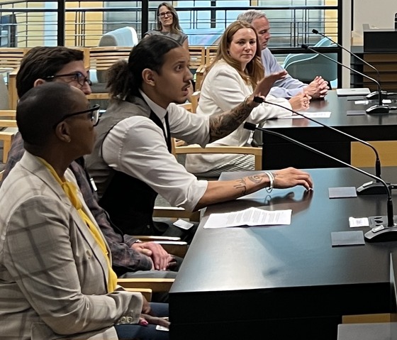 A photo of people sitting at a table with microphones providing testimony to Metro Council. 
