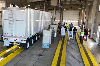 Truck parked in Inspection Bay and small group of people gathered for a presentation