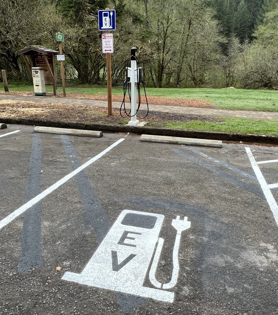 A parking space with a painted white EV station symbol, and a Level 2 charger at the head of the space