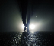 Vehicle headlights on roadway highlight pedestrian feet walking