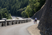 An adult and young child walk along a pedestrian path holding hands