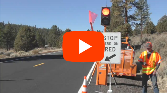 Photo of car stopped behind an AFAD with the YouTube PLAY button on top of the image.