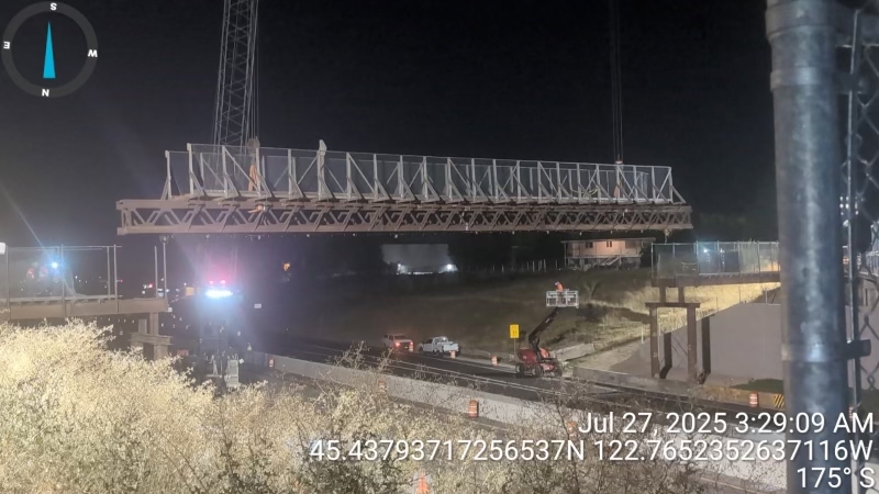 Temporary pedestrian bridge moving out of place with a crane as it's no longer needed.