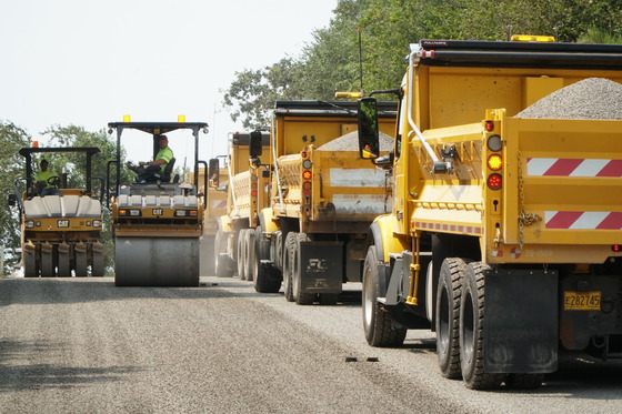 Dump trucks working a chip seal project. 