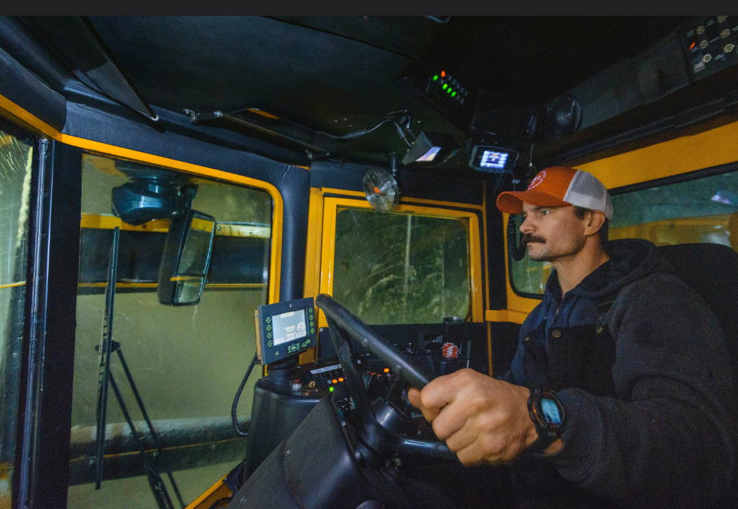 An ODOT employee drives a grader in the snow, focused on the road ahead. 