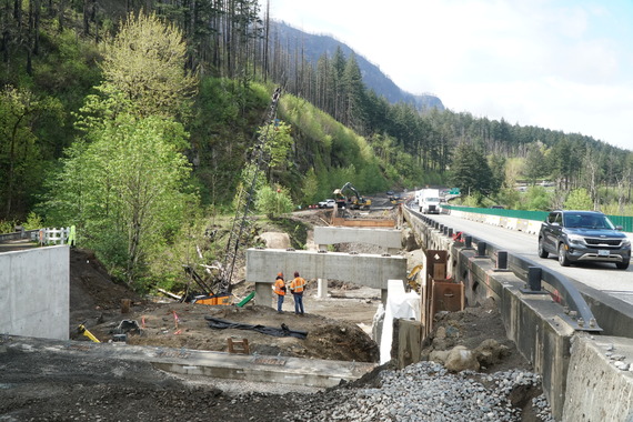 View of crews building the eastbound bridge foundation while vehicles share the westbound bridge on I-84 at McCord Creek.