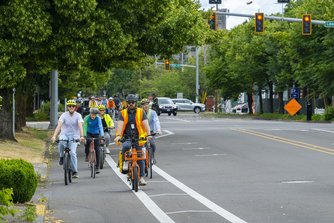 A group of people bicycle on a city street.