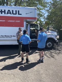 Officer talks to movers in front of a U-Haul truck