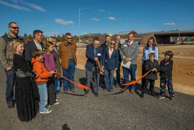 People using giant scissors to cut a ribbon.