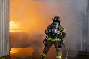 Coos Bay Firefighter spraying water on the Car Fire Prop in a garage simulation