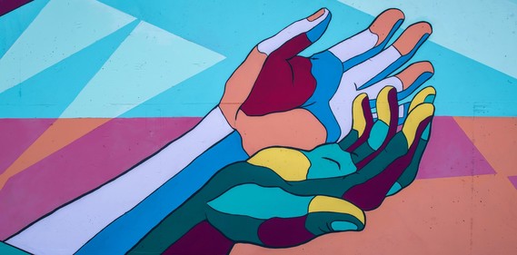 Image description: Bright, multi-color painted mural of two diferent hands coming together, with palms facing up.