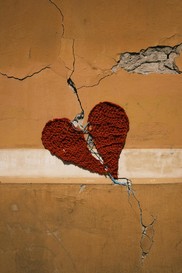 Red woven heart coming together over crack on wall