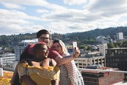 Three fat people smiling and taking a selfie on a rooftop