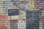 accessible entry sign with art on brick wall