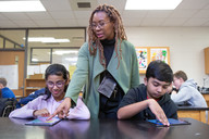 Teacher with girl and boy working on tablets