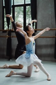 dance teacher and student in kneeling pose with arms overhead