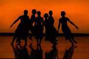 silhouettes of dancers with an orange backdrop