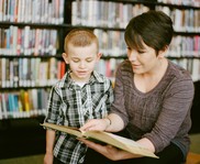 Teacher with Student Looking at Book