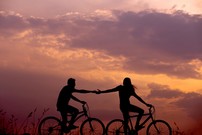 image of two people on bicycles holding hands