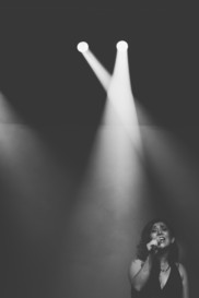 solo vocalist singing into microphone under spotlights