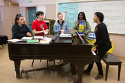 students gathered around a piano, singing