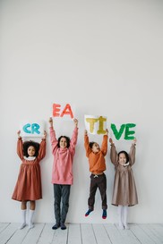 kids holding painted signs that spell creative